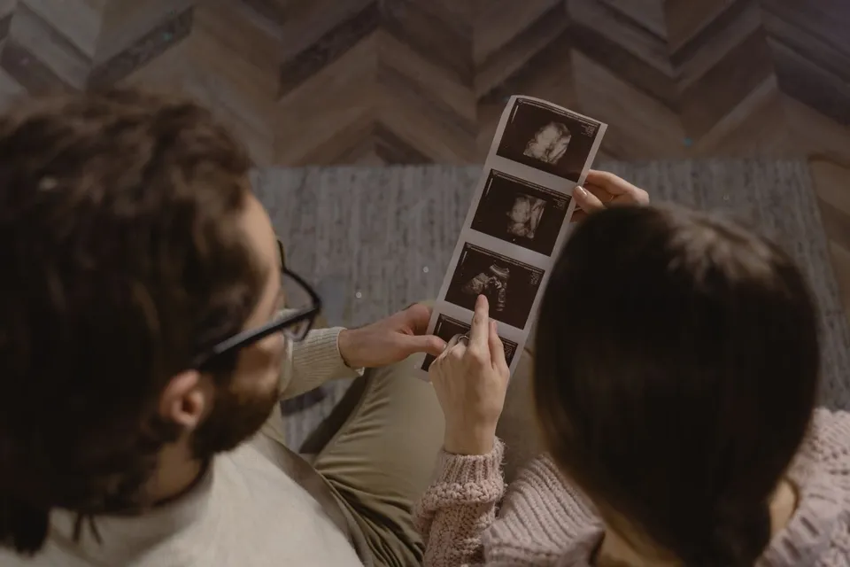 Un couple regarde ensemble les tirages de l'échographie de leur bébé