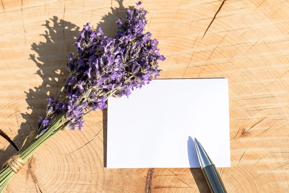Una tarjeta en blanco y un bolígrafo junto a un ramillete de lavanda sobre madera